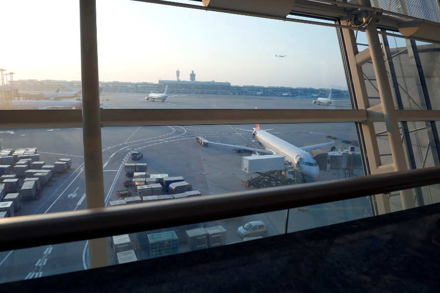 Airline jet parked at airport with planes taxing and taking off. 