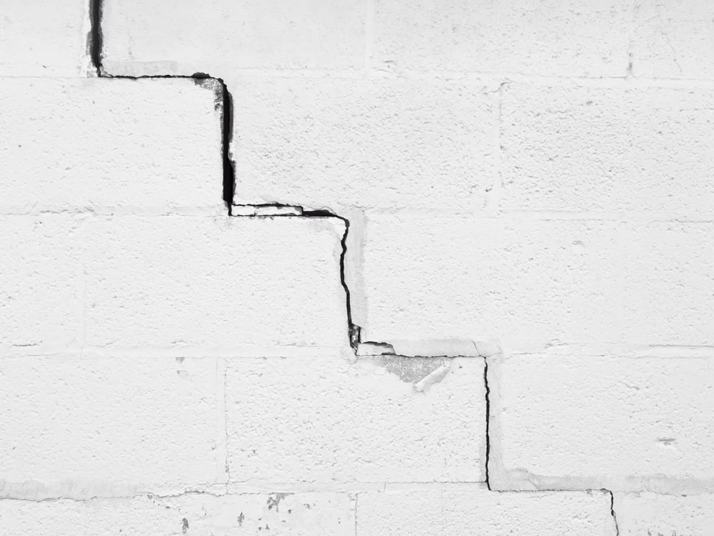 Continuous crack, angled like a stairway, along exterior white wall