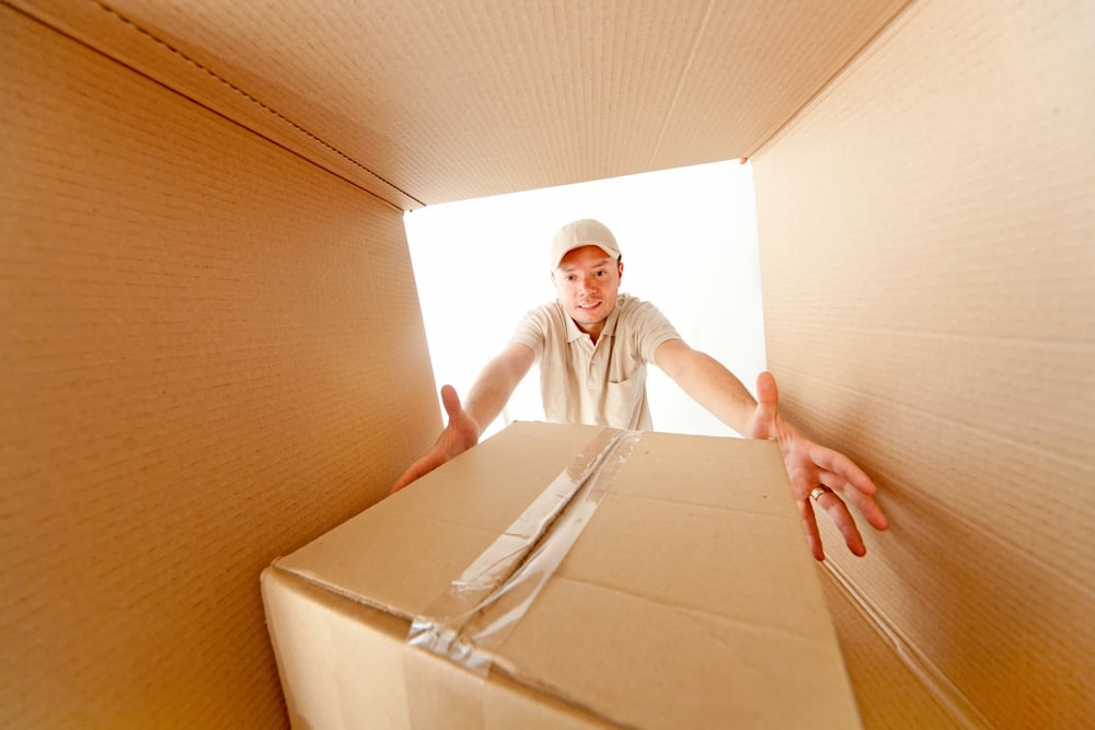 Delivery man grabbing a package from inside a mailbox