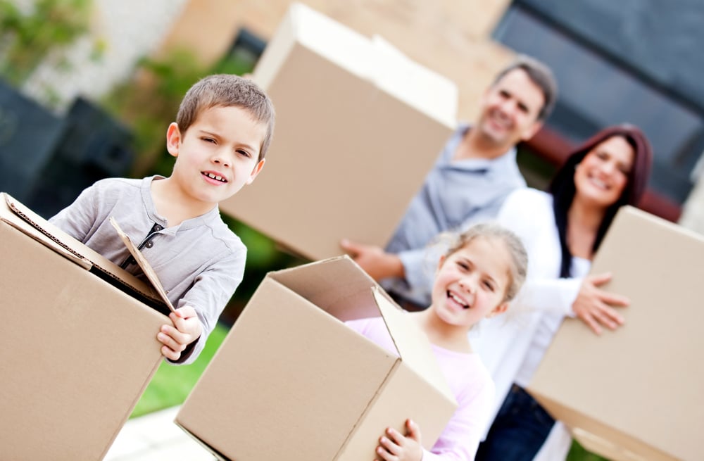 Family moving home and carrying cardboard boxes