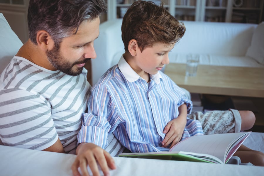 Father and son looking at photo album in living room at home