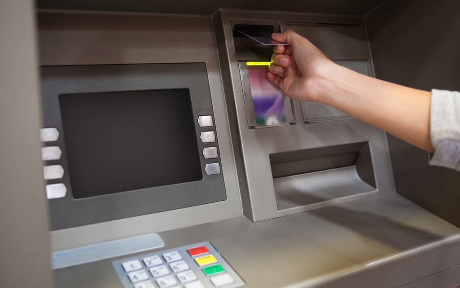 Hand inserting a credit card in an ATM