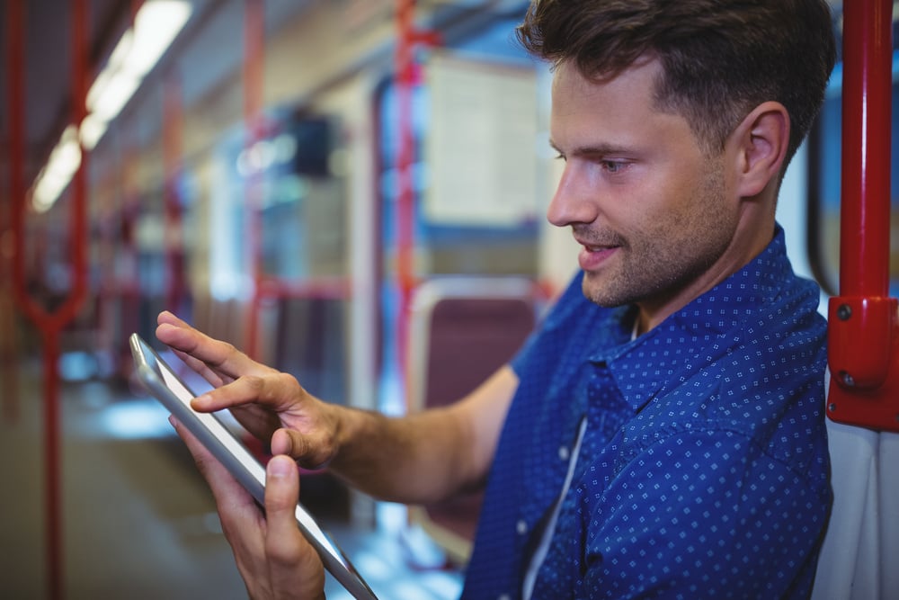 Handsome man using digital tablet while travelling in train