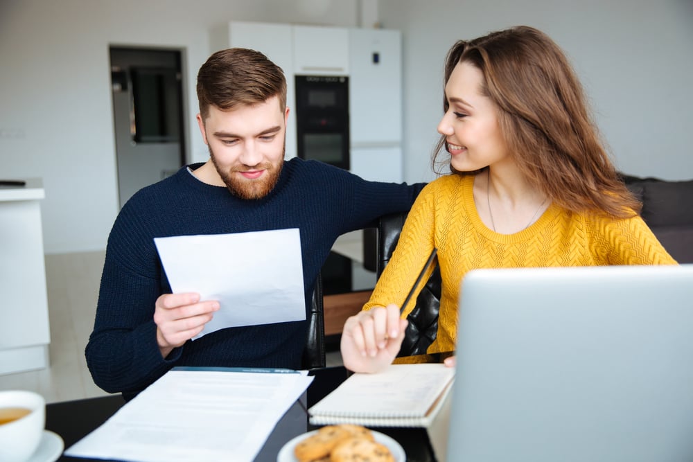 young man and woman looking at paperwork and laptop