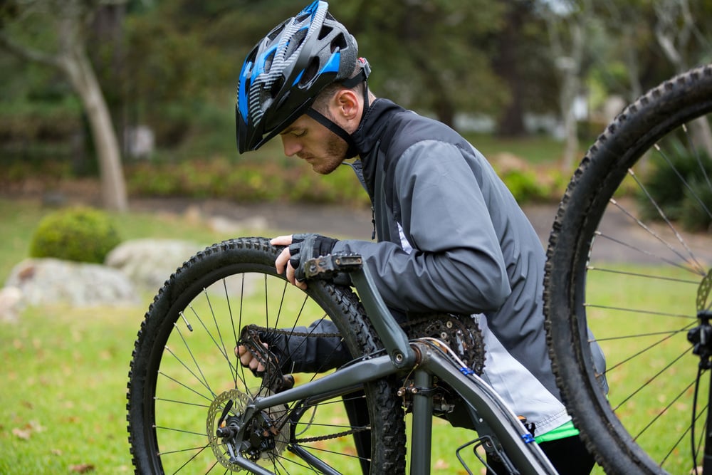 Male cyclist repairing his mountain bike in park