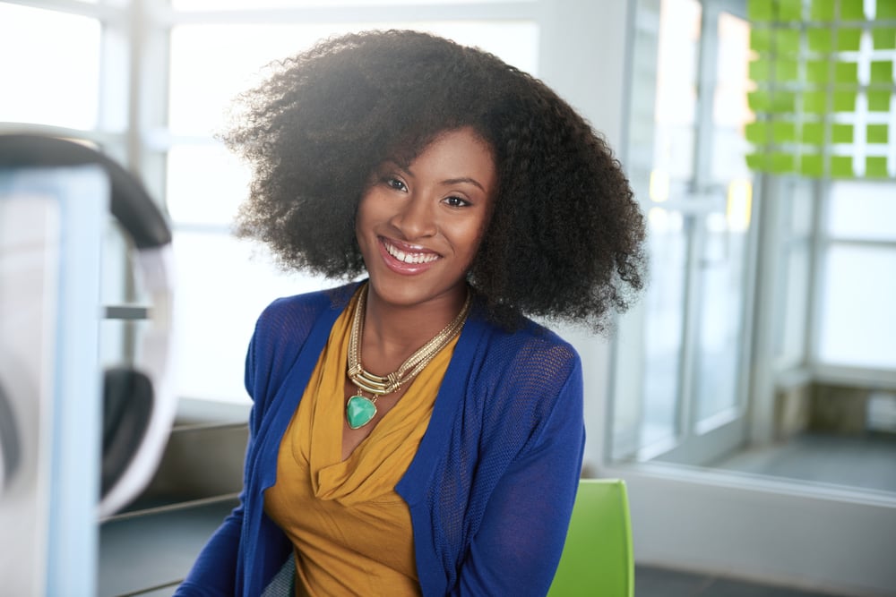 Portrait of a smiling businesswoman with at the computer in bright glass office