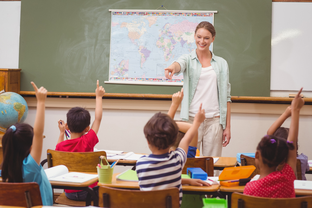 Pupils raising hand in classroom at the elementary school