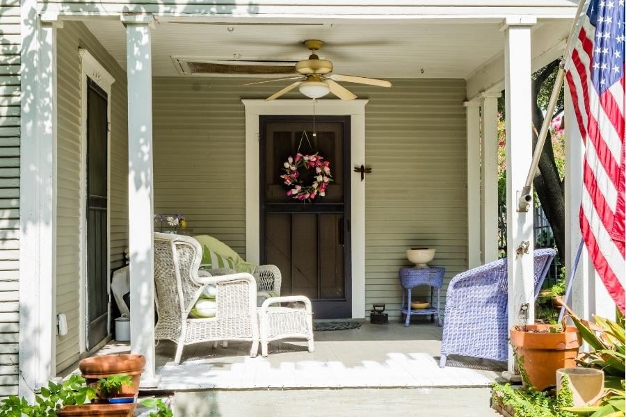 front door with wreath, covered porch and american flag