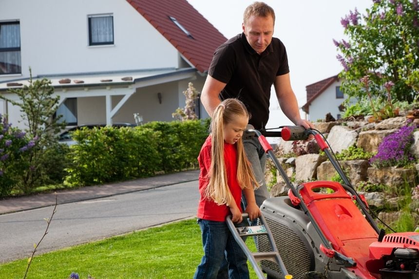father and child mowing the lawn for spring cleaning