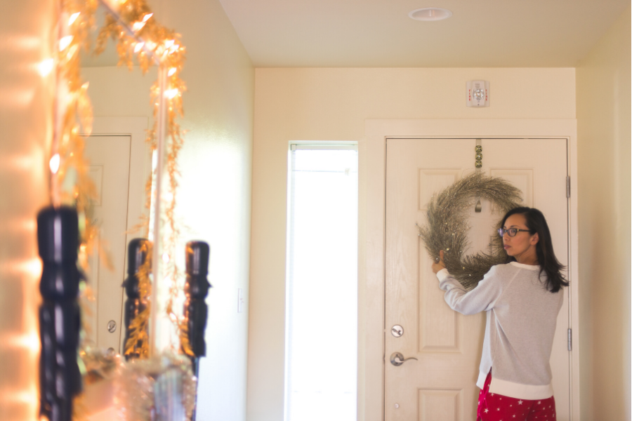 woman hanging wreath on door in holiday home staging