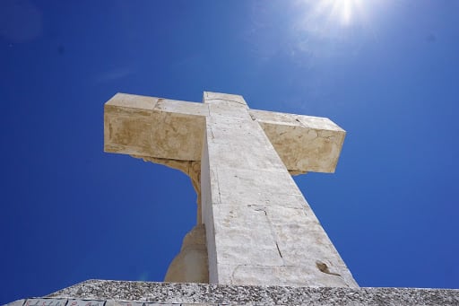 Ground view looking up at Mt Cristo Rey with blue sky and sun ray above. 