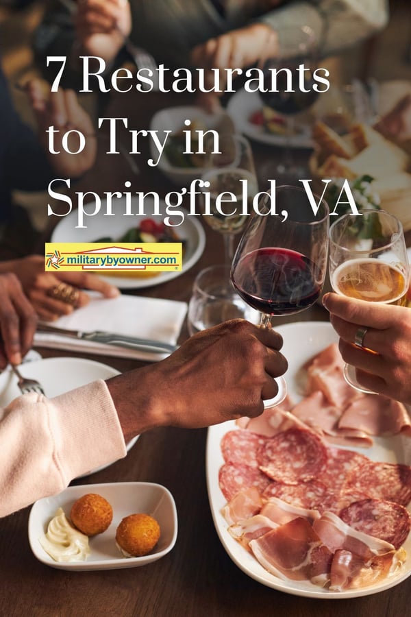 Center of busy table with people eating food, interacting, and toasting with their glasses and text, 7 Restaurants to Try in Springfield, VA