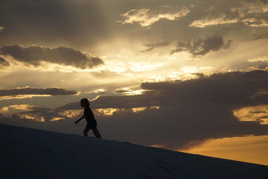 Person climbing up the sand dunes after sunset at White Sands National Monument