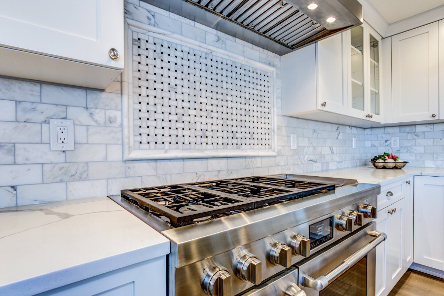 Beautiful white kitchen, stainless steel stove, and white tile backsplash in home for sale. 
