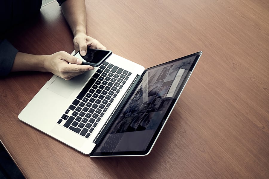 woman looking at phone and laptop