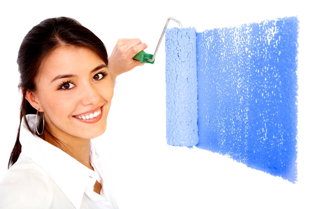 beautiful woman painting a wall with a roller - isolated over a white background