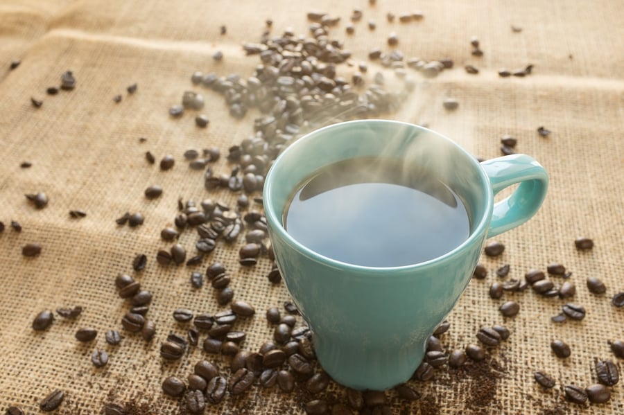 cup of steaming coffee and coffee beans