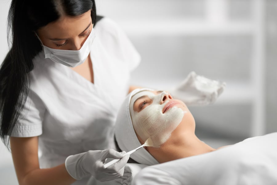 aesthetician applying cream to woman's face