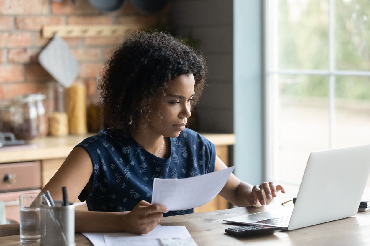 woman using laptop with paperwork on desk