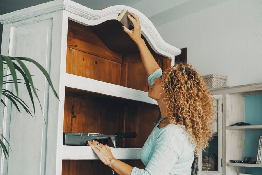 young woman refinishing an armoire