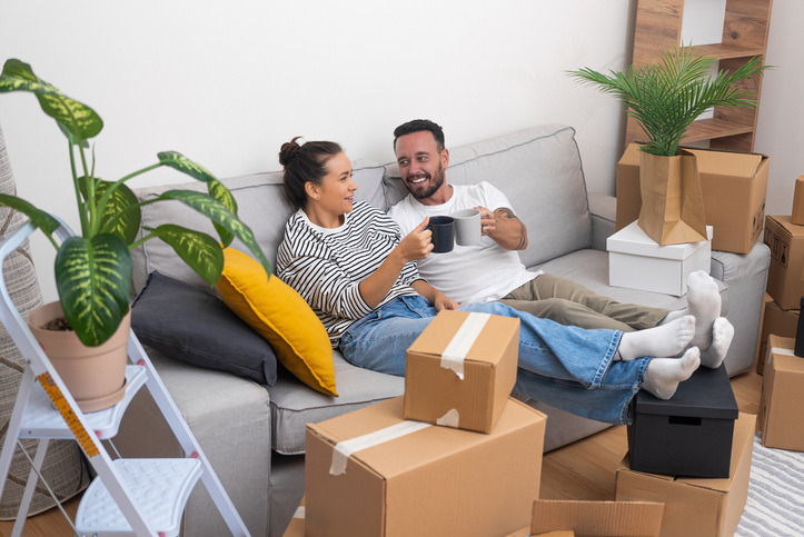 couple drinking coffee on couch surrounded by moving boxes