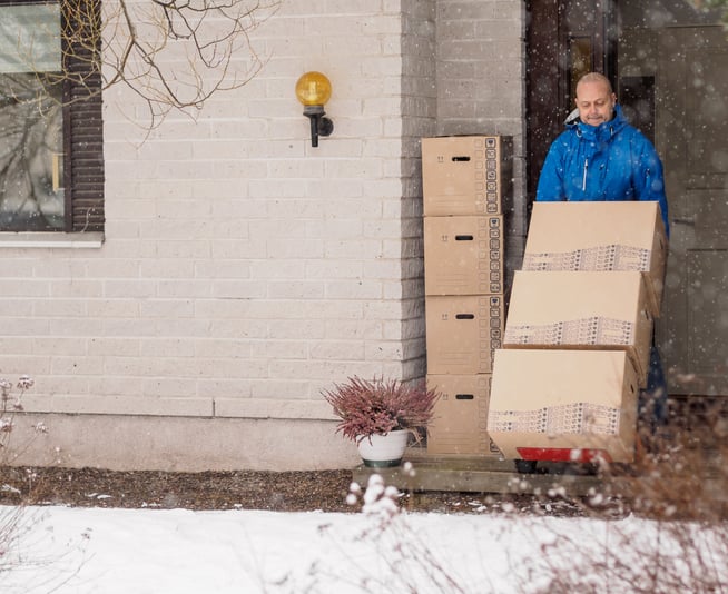 man moving boxes in winter and snow