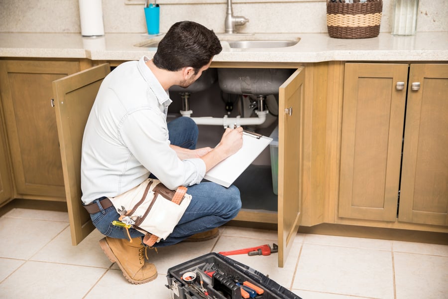 home appraiser looking at pipes under sink