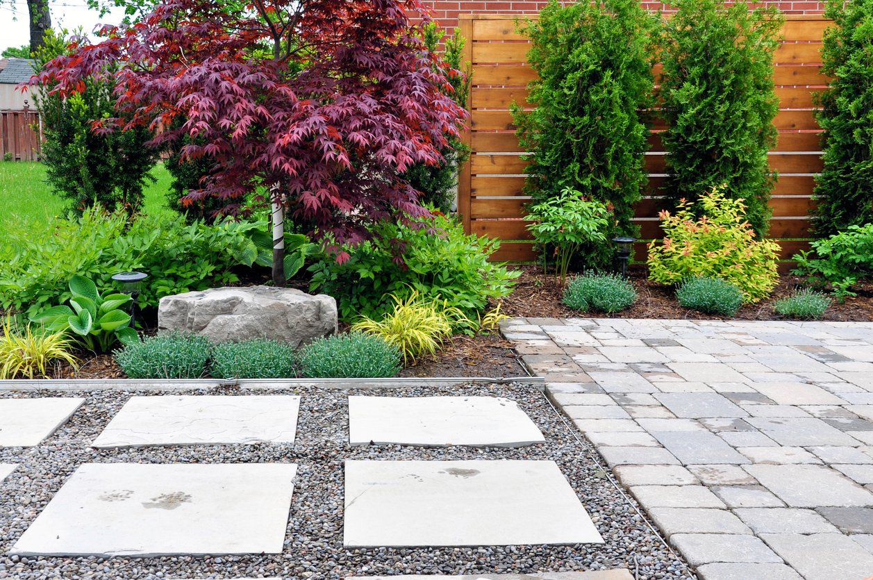 Hardscape details of a tumbled paver patio, flagstone stepping stones and horizontal cedar fence in a modern Japanese garden