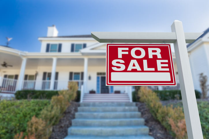 white home with steps in front of it and red for sale sign