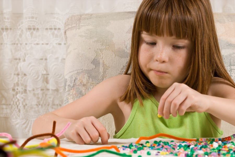 girl making a craft with beads and pipe cleaners