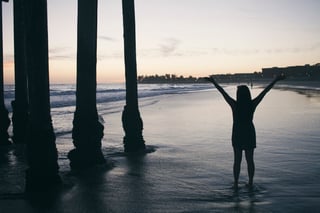 silhouette-of-woman-standing-with-arms-raised-in-the-water