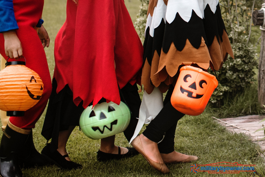 children trick or treating holding plastic buckets shaped like pumpkins