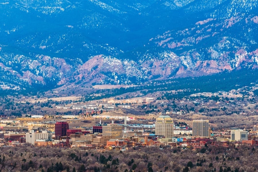 Photo of downtown Colorado Springs and skyline with mountains at dusk. 