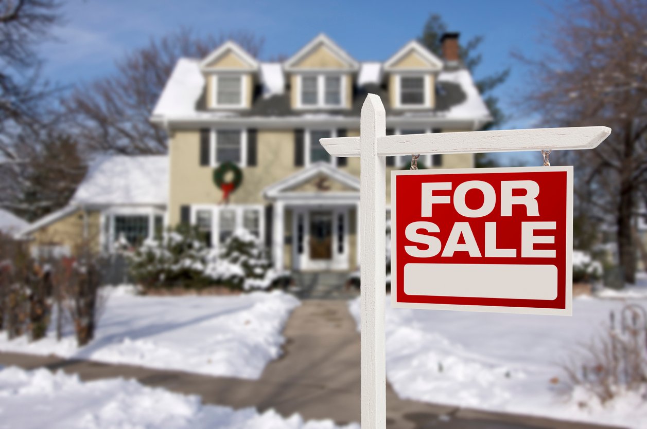 home with snow outside and for sale sign in yard