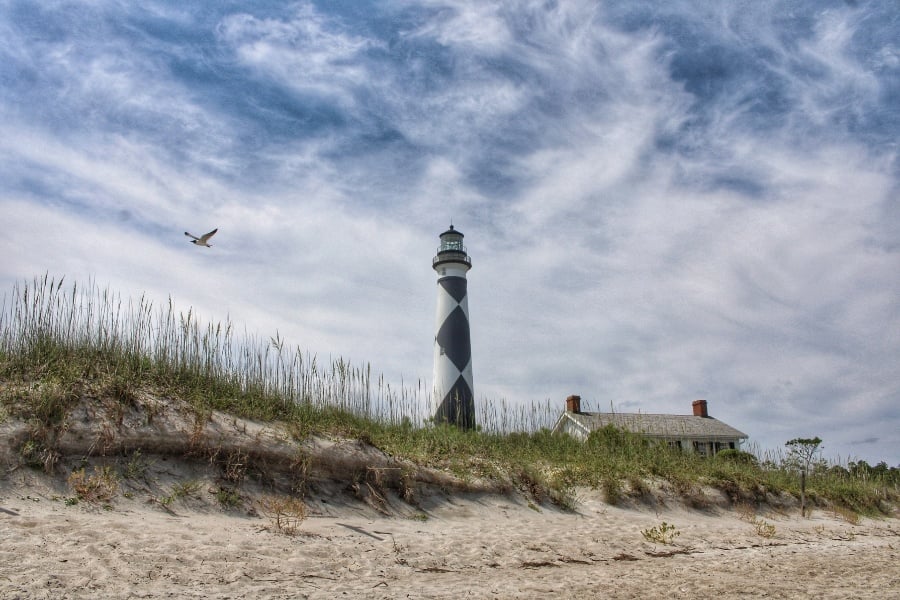 Photo of Cape Lookout National Seashore lighthouse and white building on beach in North Carolina 