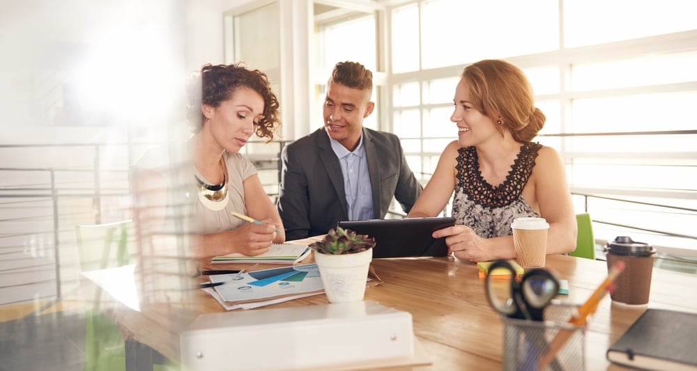 Image of three succesful business people using a tablet during at meeting.